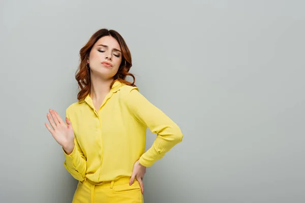 Smug woman showing refuse gesture while standing with hand on hip on grey — Stock Photo
