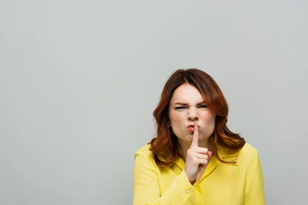 Displeased woman showing hush gesture while looking at camera isolated on grey — Stock Photo