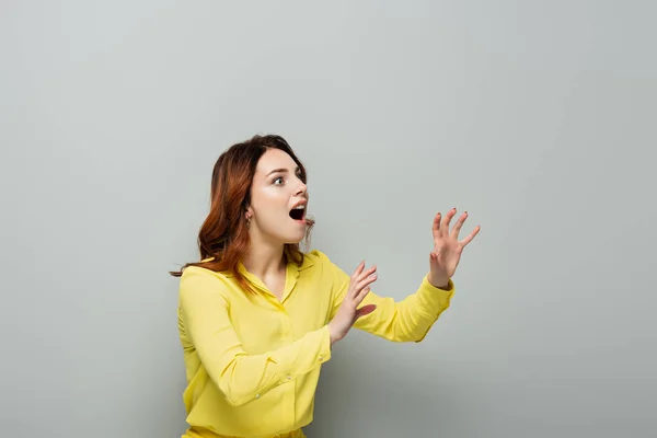 Astonished woman looking away while standing with grabbing hands on grey — Stock Photo