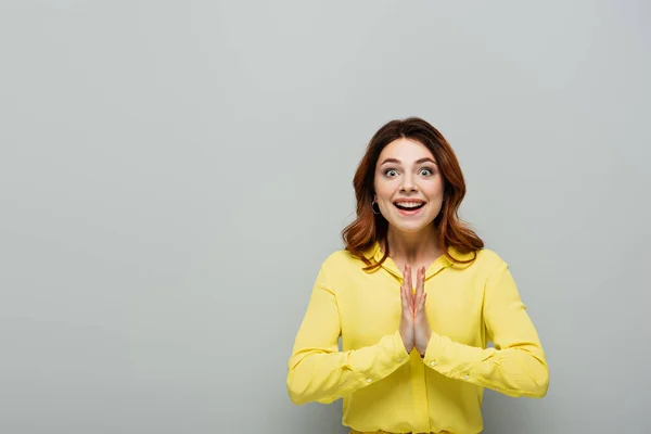 Cheerful woman clapping hands and smiling at camera on grey — Stock Photo