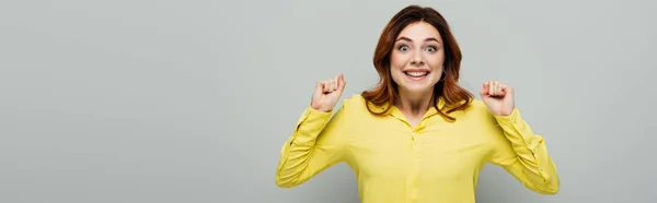 Aufgeregte Frau in gelber Bluse mit geballten Fäusten auf grauem Transparent — Stockfoto