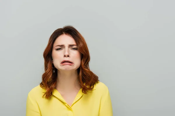 Discouraged woman looking at camera and grimacing isolated on grey — Stock Photo