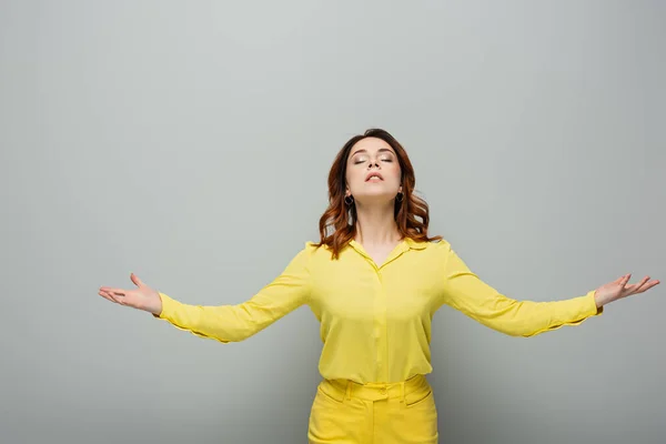 Young woman in yellow clothes meditating with closed eyes on grey — Stock Photo