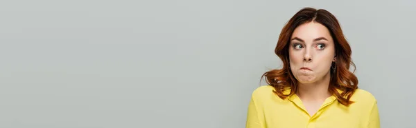 Confused woman in yellow blouse looking away isolated on grey, banner — Stock Photo