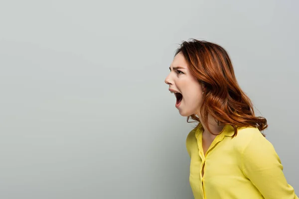 Angry woman in yellow short screaming while looking away on grey — Stock Photo
