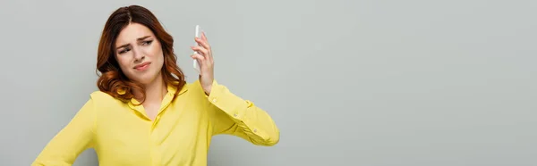 Недовольная женщина дистанцируется от мобильного телефона во время разговора на сером, баннере — стоковое фото