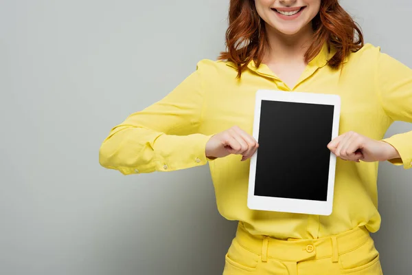Ausgeschnittene Ansicht einer fröhlichen Frau, die ein digitales Tablet mit leerem Bildschirm auf grau zeigt — Stockfoto