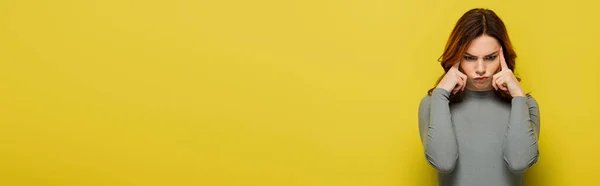 Thoughtful woman in grey pullover touching head on yellow, banner — Stock Photo