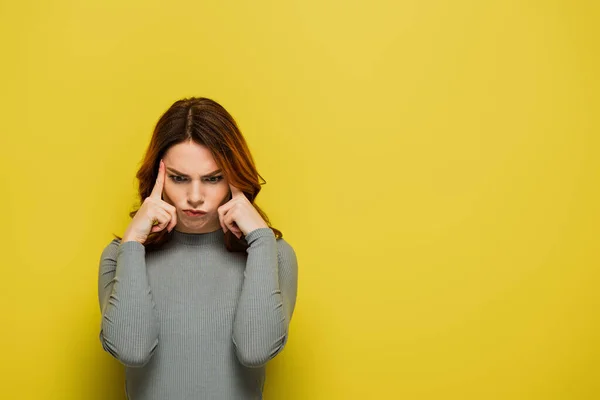 Seria donna in camicia grigia che tocca la testa pensando al giallo — Foto stock