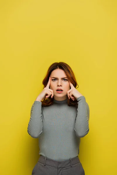 Worried woman touching head while looking at camera on yellow — Stock Photo