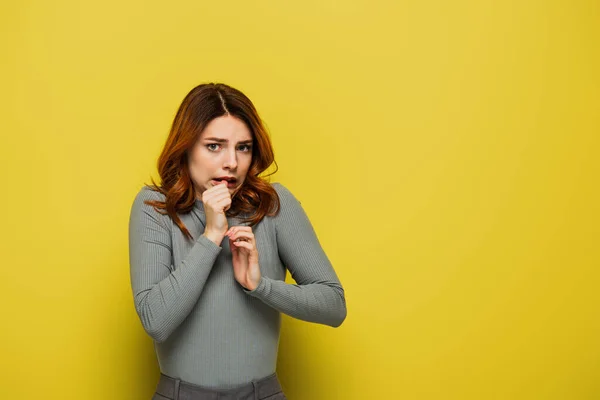 Anxious woman looking at camera while holdings hands near face on yellow — Stock Photo