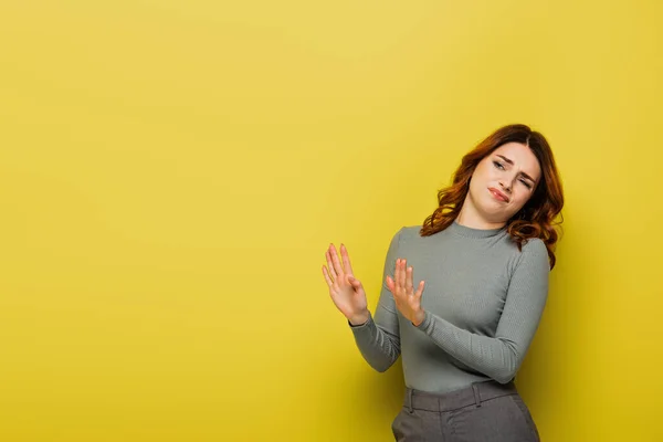 Mujer disgustada mostrando gesto de stop mientras mira hacia otro lado en amarillo - foto de stock