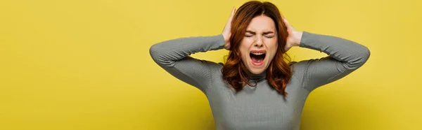 Giovane donna urla mentre tocca la testa sul giallo, striscione — Foto stock