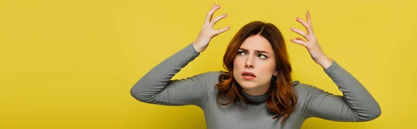 Напружена жінка з кучерявим жестом для волосся ізольована на жовтому, банер — стокове фото