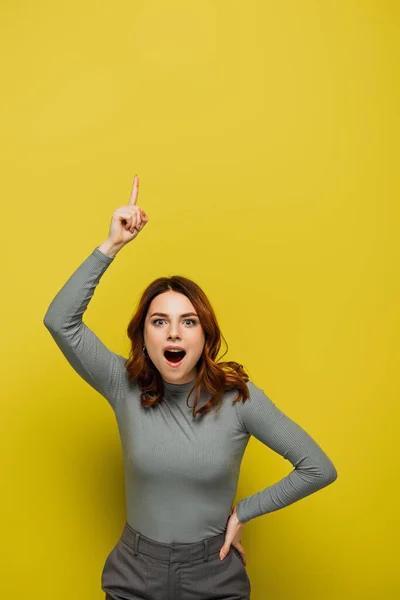 Amazed woman having idea and looking at camera on yellow — Stock Photo