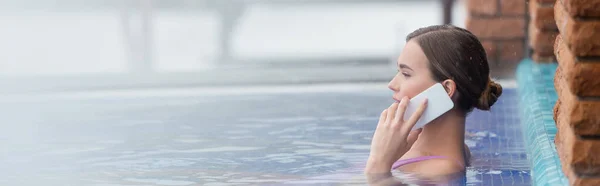 Seitenansicht einer Frau im Badeanzug, die beim Baden im Freibad mit dem Smartphone spricht, Banner — Stockfoto