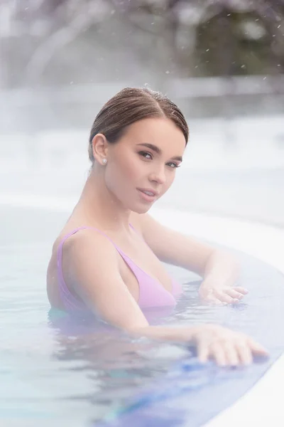 Dampf in der Nähe einer jungen Frau, die beim Baden im Thermalfreibad in die Kamera schaut — Stockfoto