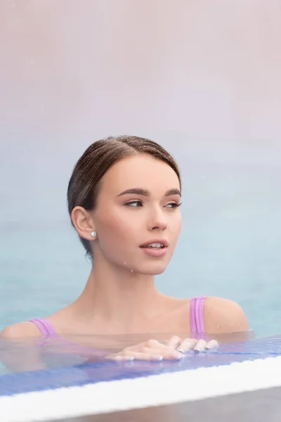 Dampf in der Nähe einer jungen Frau, die wegschaut und im Thermalfreibad schwimmt — Stockfoto