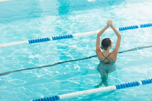 Back view of young woman standing in swimming pool — Stock Photo