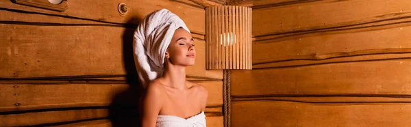 Zufriedene Frau in Handtüchern in Sauna sitzend, Banner — Stockfoto