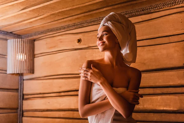 Happy woman relaxing in wooden sauna on blurred background — Stock Photo