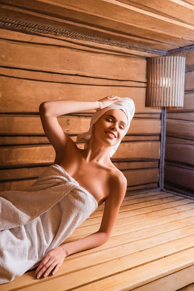 Fröhliche Frau mit Hand nahe Kopfstütze auf Sitz in Sauna — Stockfoto