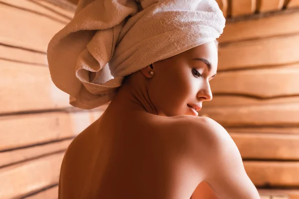 Hemdlose Frau mit Handtuch auf dem Kopf entspannt sich in der Sauna — Stockfoto