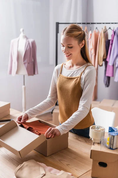 Happy fashion boutique owner packing cardboard boxes at workplace — Stock Photo