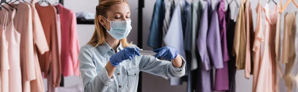 Young showroom owner in medical mask and latex gloves, taking photo on smartphone, banner — Stock Photo