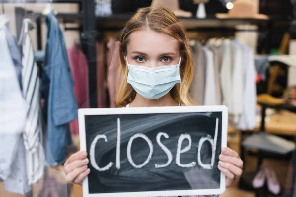 Board with closed lettering in hands of showroom owner wearing medical mask — Stock Photo