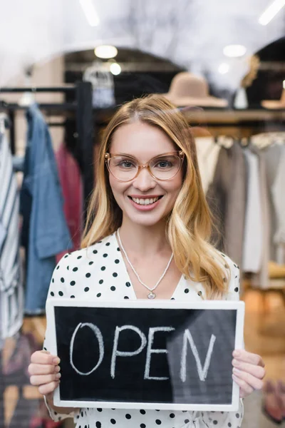 Erfolgreiche Geschäftsfrau hält Tafel mit offenem Schriftzug im Kleiderladen — Stockfoto