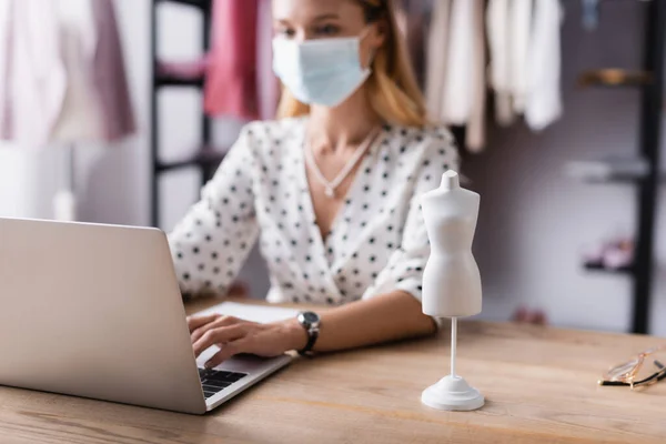 Selective focus of mannequin model near showroom owner in medical mask on blurred background — Stock Photo