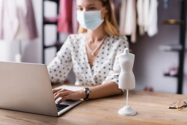 Selektiver Fokus des Schaufensterpuppenmodells in der Nähe des Showroom-Besitzers in medizinischer Maske auf verschwommenem Hintergrund — Stockfoto