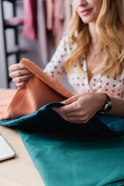 Cropped view of showroom owner comparing samples of cloth on blurred background — Stock Photo