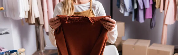 Cropped view of showroom owner holding sweater, banner — Stock Photo