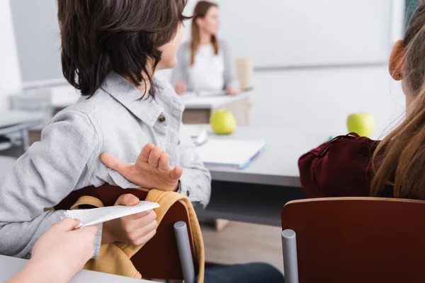 Bambino che dà nota al compagno di classe durante la lezione a scuola — Foto stock