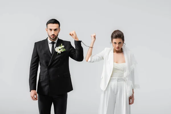 Interracial couple of newlyweds in handcuffs looking at camera isolated on grey — Stock Photo