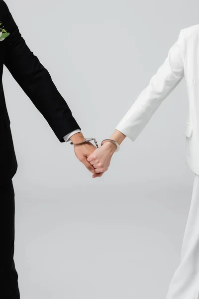Ausgeschnittene Ansicht von Braut und Bräutigam in Handschellen, die Hände isoliert auf grau halten — Stockfoto