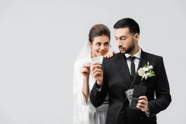 Arabo sposo dando denaro alla sposa sorridente isolato su grigio — Foto stock
