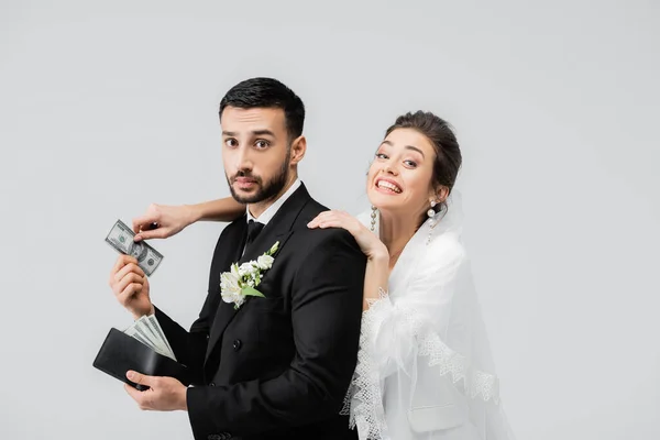 Novio musulmán dando dinero a la novia alegre aislado en gris - foto de stock