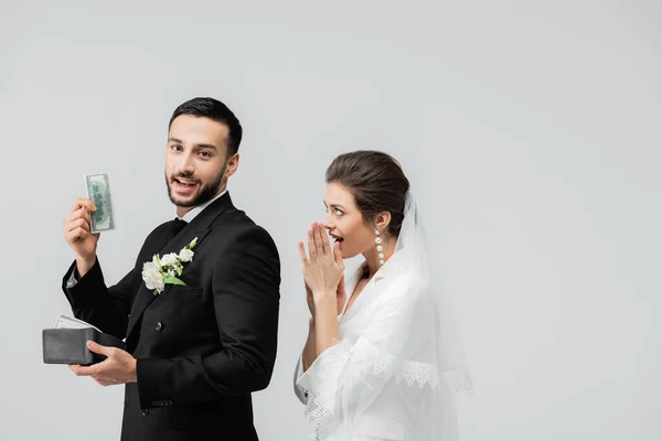 Smiling arabian groom holding money near excited bride isolated on grey — Stock Photo