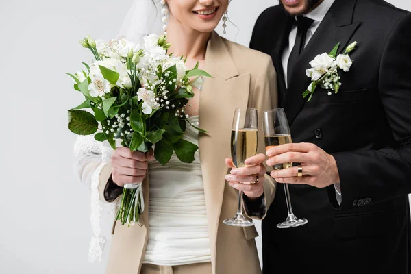 Vista recortada de los recién casados sonrientes brindando con champán aislado en gris - foto de stock