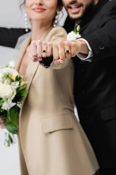 Partial view of newlywed couple showing wedding rings on blurred background isolated on grey — Stock Photo