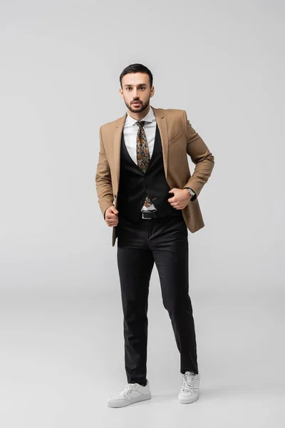 Full length view of trendy muslim man looking at camera while posing on grey — Stock Photo