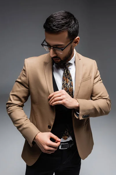 Young arabian man in trendy clothes touching blazer on grey — Stock Photo