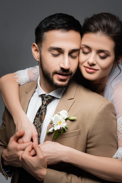 Young, joyful, interracial newlywed couple with closed eyes isolated on grey — Stock Photo