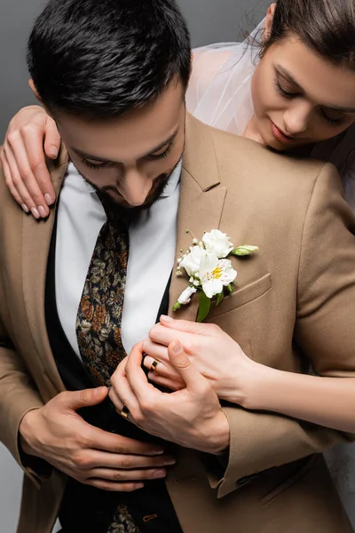 Arabian man in blazer with boutonniere touching hand of bride isolated on grey — Stock Photo