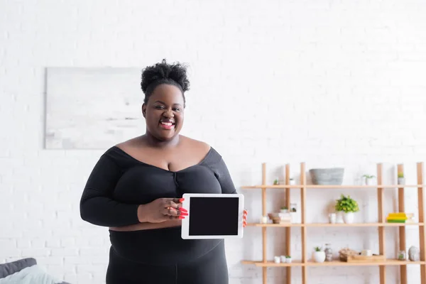 Gai afro-américain plus la taille femme en tenue de sport tablette numérique avec écran blanc — Photo de stock