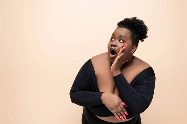 Surprised african american plus size woman looking away isolated on beige — Stock Photo