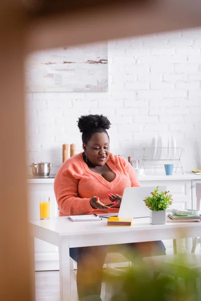 Happy african american plus size freelancer using laptop at home — Stock Photo